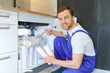 © Serhii - Plumber installs or change water filter. Replacement aqua filter. Repairman installing water filter cartridges in a kitchen. Installation of reverse osmosis water purification system.