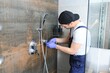 © Serhii - Plumber installing water taps shower stall, work in bathroom.