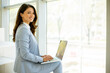 © BGStock72 - Young business woman sitting on the stairs on office hallway and working on laptop