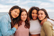 © bernardbodo - Portrait of four diverse young girl friends standing together on beach.