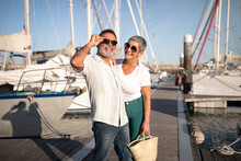 Senior Spouses Having Fun Posing Near Yachts At Marina Outdoors
