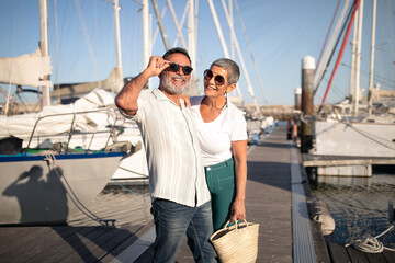 senior spouses having fun posing near yachts at marina outdoors