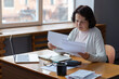 © Юлия Завалишина - Middle aged senior woman sit with laptop and paper document, Pensive older mature lady reading paper bill pay online at home managing bank finances calculating taxes planning loan debt pension payment
