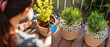© Pasko Maksim  - A gardener woman in gloves is planting flowers in pots on the terrace. Gardening cocept