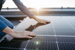 © Halfpoint - Close up of woman touching solar panels on the roof.