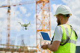 Fototapeta  - Drone operated by safety engineering inspector. Construction worker piloting drone on building site