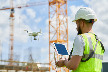 Wall Mural - drone operated by safety engineering inspector. construction worker piloting drone on building site