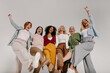 © gstockstudio - Multi-ethnic group of cheerful mature women embracing and dancing against grey background