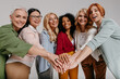 © gstockstudio - Multi-ethnic group of happy mature women holding hands together against grey background