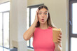 young pretty woman feeling extremely shocked and surprised. take away coffee concept