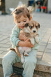 Little kid girl playing with cute little puppy in sunny summer garden. Little girl holding puppies. Child with pet dog. Kid and animals friendship.