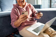 © Baba Images - Middle aged latin man online shopping on his laptop and phone at home