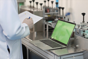 Canvas Print - Inspector man or worker male hands doing quality of mask and medical face mask production line with blank green screen computer, Industry and factory concept.