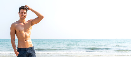 Portrait of smiling happy, relax handsome sexy man, male showing muscular fit body enjoying and relax standing on the tropical sea, beach.Summer vacations and travel