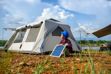 child boy use solar cell near camping tents schemes to store solar energy to generate electricity fo