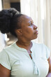 © WavebreakMediaMicro - Thoughtful senior african american woman standing looking out of window at home