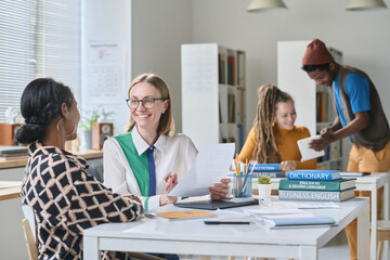 Smiling teacher speaking foreign language with student during lesson in class