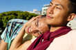© Wavebreak Media - Happy biracial gay male couple sitting on bench and embracing on sunny promenade by the sea