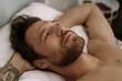 © Cavan Images - Handsome man in bed after sleep wakes up and starts a new day.