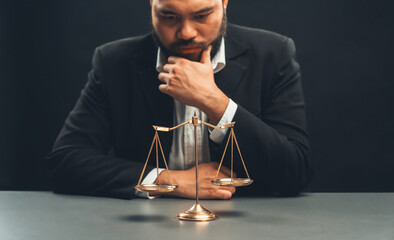 Focus scale balance with blur lawyer sitting at his desk with worried and exhausted expression, feeling weight of pressure and stress of making hard decision on verdict. equility
