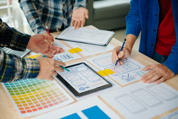  UX developer and ui designer brainstorming about mobile app interface wireframe design with customer breif and color code at modern office..