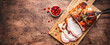 Baked pork loin on rustic wooden cutting board with spices, herbs and cranberries. Wood kitchen table background, top view banner with copy space