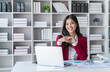 © nopparat - Asian happy beautiful businesswoman in red suit work in workplace.Business Female working on a laptop computer in her workstation.
