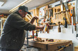 © PoppyPix - male carpenter using an old brace and creating a hole in a wooden plank, medium shot. High quality photo