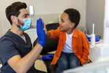 Fototapeta  - Doctor and little patient doing high five and looking contented