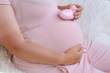 Wall Mural - middle-aged pregnant woman in pink t-shirt holding her belly, waiting for newborn, concept of pregnancy reproduction, in vitro fertilization, planning late pregnancy after 40 years, selective focus