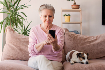 Relaxed mature old 60s woman with phone at home