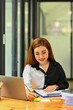 © Prathankarnpap - Smiling female employee sitting in front of laptop and writing on sticky notes