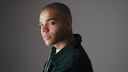 Wall Mural - young bald man in a jacket posing for the camera, medium closeup grey background. High quality 4k footage