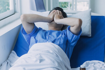 young injured man in hospital room sitting alone in pain looking negative and worried for his bad health condition sitting on chair suffering depression on a sad lonely medical background