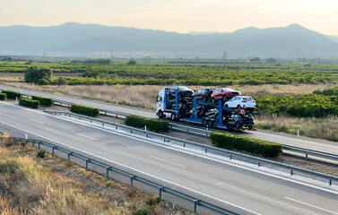 Wall Mural - Car carrier trailer transports cars on highway. Auto transport and car shipping services concept. Truck with Semi-remorque. Cars Shipping. Car transportation. Car Transport Trailer on Spain motorway