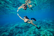 Young Asian Woman Wearing A Black Bikini Snorkelling In The Ocean Above A Coral Reef