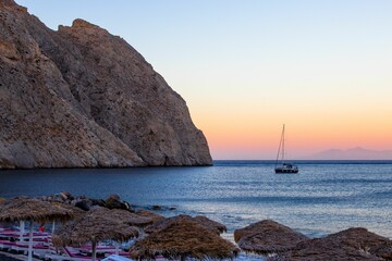 Wall Mural - Scenic view of a boat sailing in the ocean during a beautiful sunset in Oia, Santorini