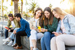 © Xavier Lorenzo - Teenage group of young friends using mobile phones outdoors. Millennials having fun watching social media content on smartphone app. Technology and youth community concept.