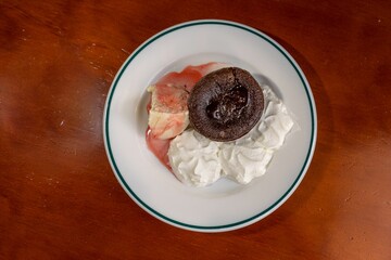 Sticker - Top view of a chocolate brownie served on a white plate with whipped cream and vanilla ice-cream