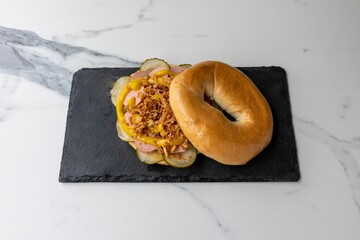 Sticker - Delicious bagel with meat and fried onions served on the black board on the marble table