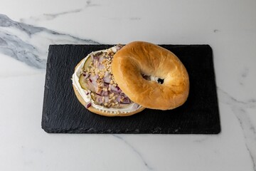 Sticker - Delicious bagel with onions served on the black board on the marble table