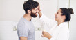 © Emil L/peopleimages.com - Couple, face skincare cream and bathroom with smile, helping hand and morning together in home. Woman, man and skin wellness for help, care or laughing with product for lifestyle, beauty or health