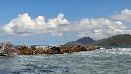 Wall Mural - Saint Kitts ocean landscape, waves breaking over rocks on a sunny day.