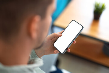 Wall Mural - man using smartphone with blank screen and frameless modern design while sitting on the sofa in home
