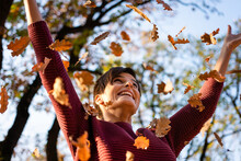 Happy Woman Throwing Autumn Leaves In Nature