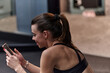 © .shock - A fit woman in the gym taking a break from her training and uses her smartphone, embracing the convenience of technology to stay connected
