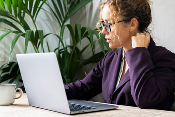 Wall Mural - Businesswoman working on laptop at office. Adult female entrepreneur using computer on the table. Professional freelance job activity. New business online. Lady manager elegant suit and eyeglasses