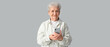 © Pixel-Shot - Senior woman with modern mobile phone on grey background
