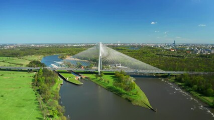 Wall Mural - Cable-stayed Redzinski Bridge built over small green island on Oder river. Pylon bridge and lush greenery by Wroclaw under blue sky aerial view