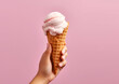 Hand holding ice cream cone on pink background. Banner, advertisement